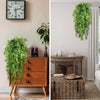 Artificial green hanging vine greenery displayed next to a wooden cabinet and clock.