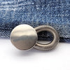 Silver extender buttons attached to a denim fabric background