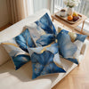 Blue and gold abstract leaf print cushion covers displayed on a light sofa.