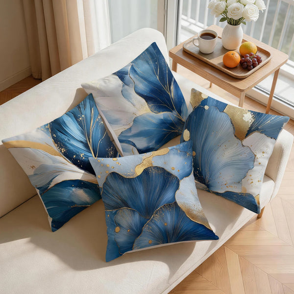 Blue and gold abstract leaf print cushion covers displayed on a light sofa.