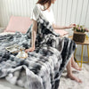A woman is sitting on a white rug draped in a gray and white gradient bubble fleece throw blanket.