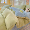 A cozy milk velvet bedding set featuring a duvet cover and pillows in soft olive green and blue tones.
