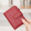 A close-up of a red croc-embossed PU leather bifold wallet being held by a hand.