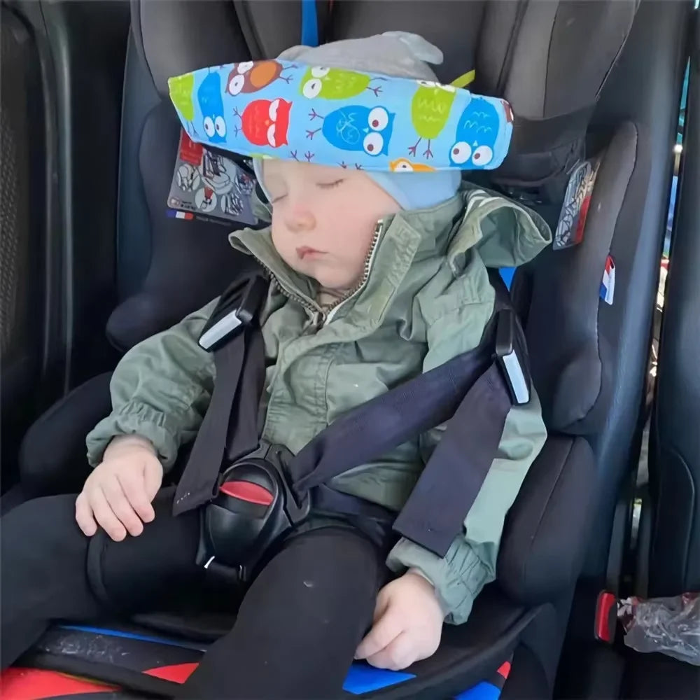 A baby is seated in a car seat with an adjustable sleeping headrest and safety belt strap.
