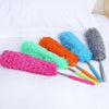 A collection of colorful telescopic microfiber dusters with flexible stainless steel handles displayed on a white bed.