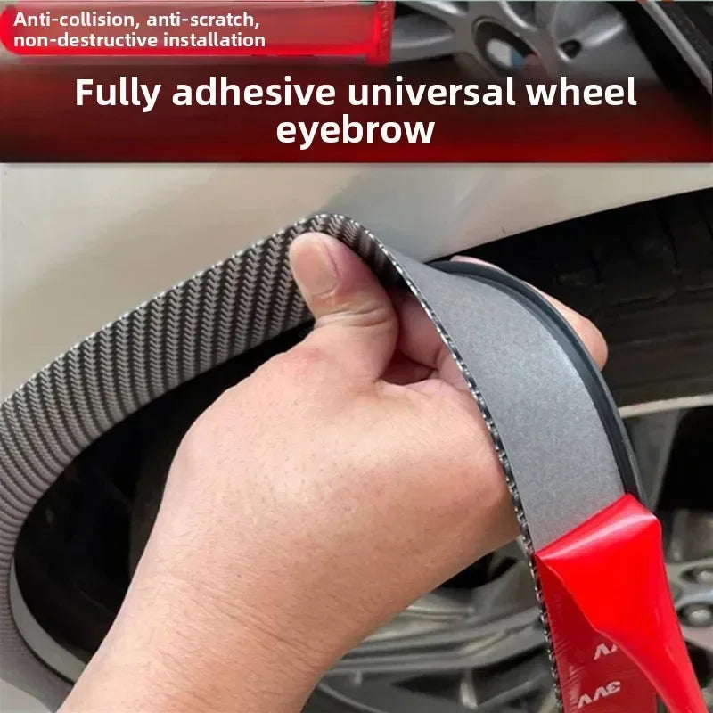 A hand is applying a fully adhesive universal wheel eyebrow trim to a car wheel, showing the black and carbon fiber texture.