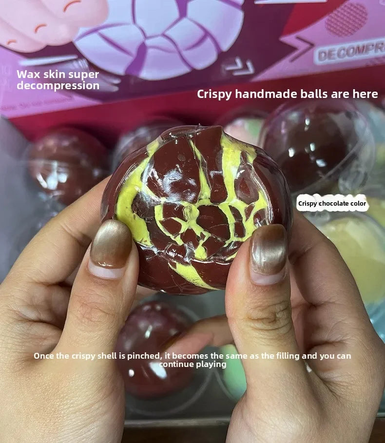 Hands hold a brown and yellow squishy stress ball, demonstrating its crispy shell feature.