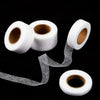 Rolls of white iron-on hemming tape with loose strands unwinding from one roll