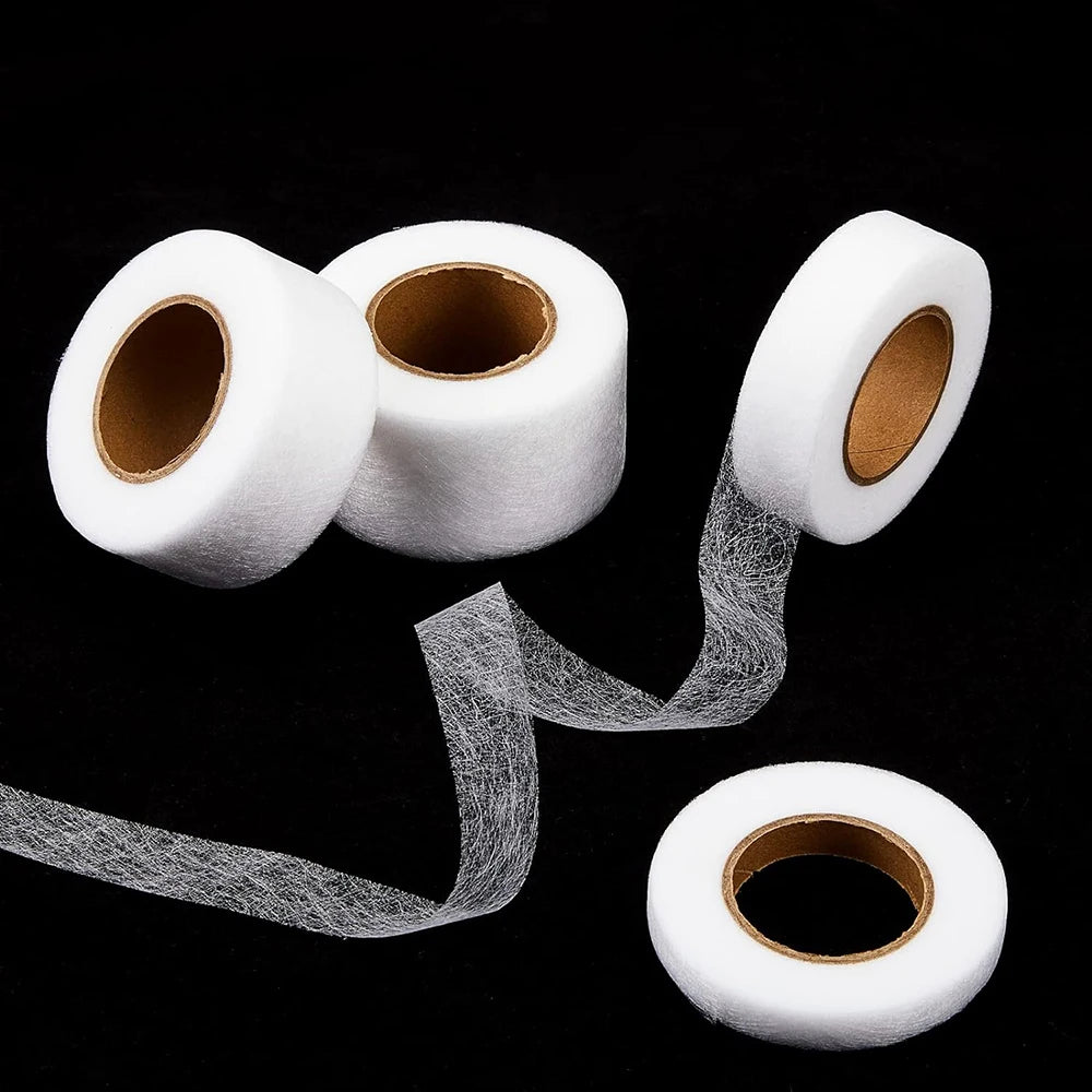 Rolls of white iron-on hemming tape with loose strands unwinding from one roll