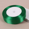A roll of lustrous satin ribbon in emerald green on a white core for gift wrapping and crafts.