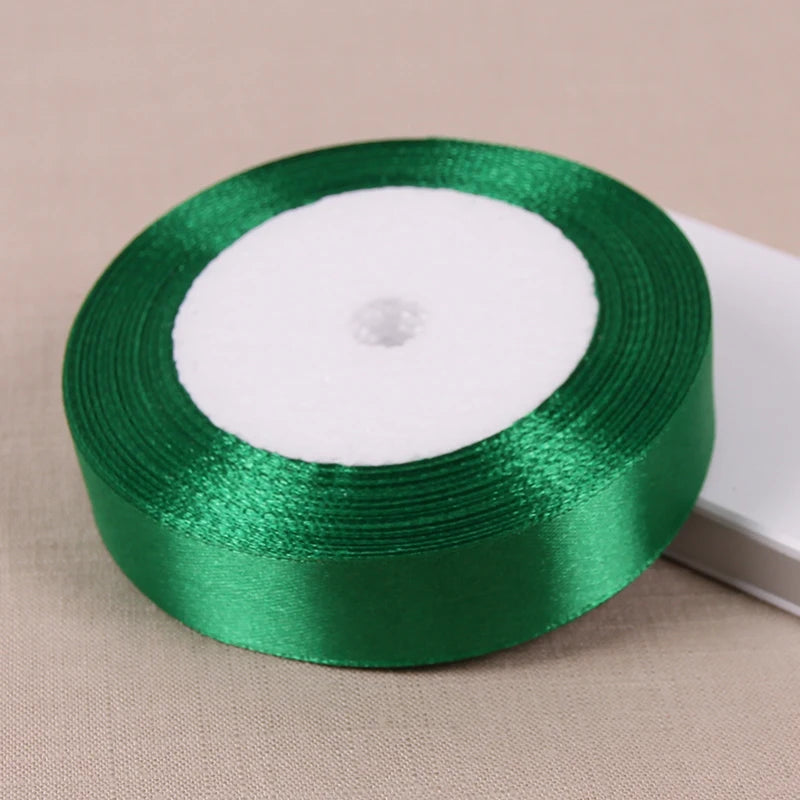 A roll of lustrous satin ribbon in emerald green on a white core for gift wrapping and crafts.