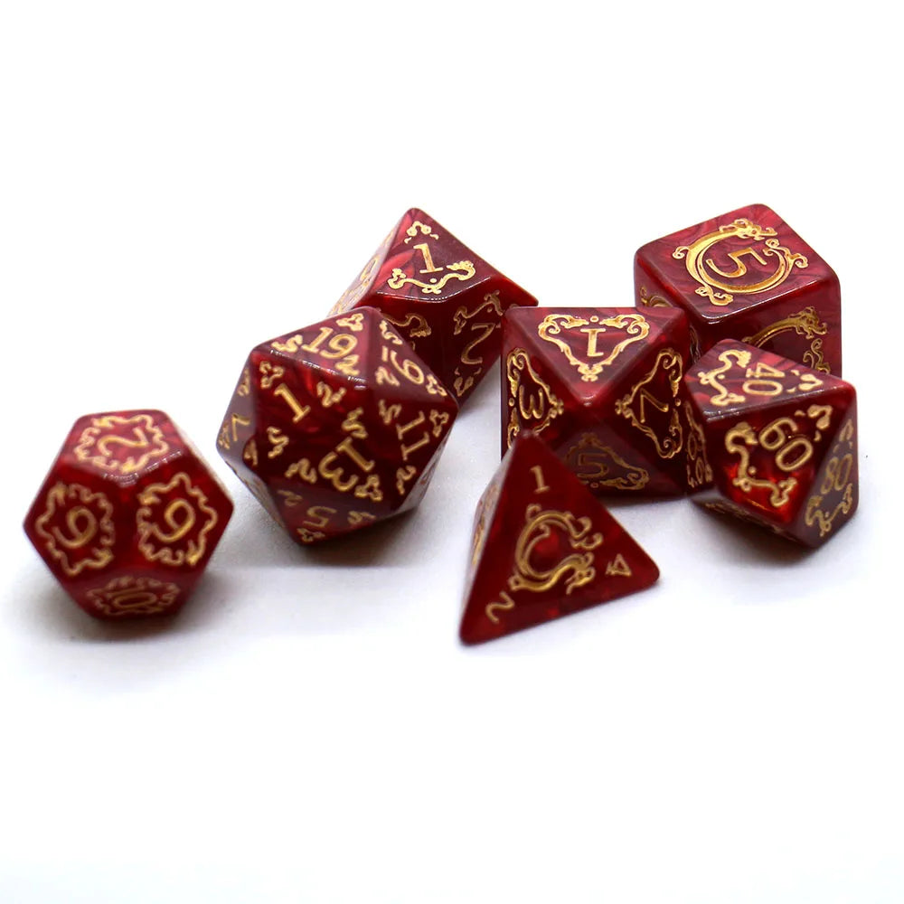A set of red polyhedral dice with gold embellishments scattered on a white surface.