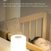 A white LED table lamp emitting a soft light, shown on a wooden surface next to a person's head.