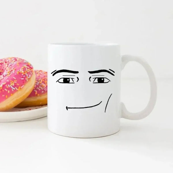 A white ceramic coffee mug featuring a simple black line drawing of a face with wide eyes and a slight smile.