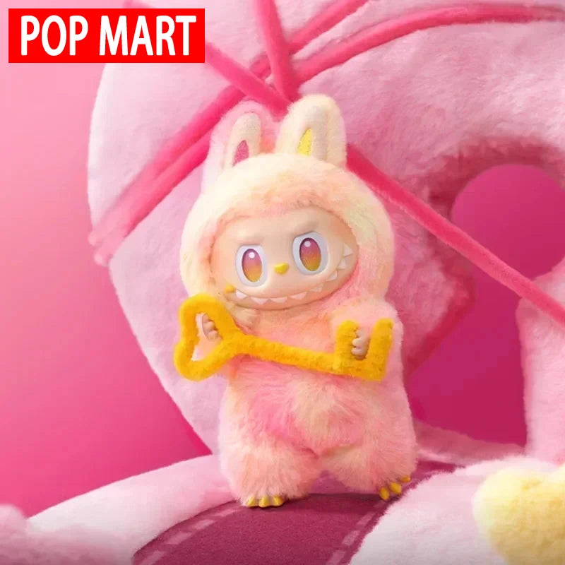 A pink Labubu Big Into Energy plush doll with yellow accents is shown against a pink background.