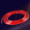 A coil of flexible red PVC car bumper protection strip lying on a dark surface.