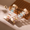 A wooden rain rattle sensory toy with colorful beads and wooden components resting on a woven mat.