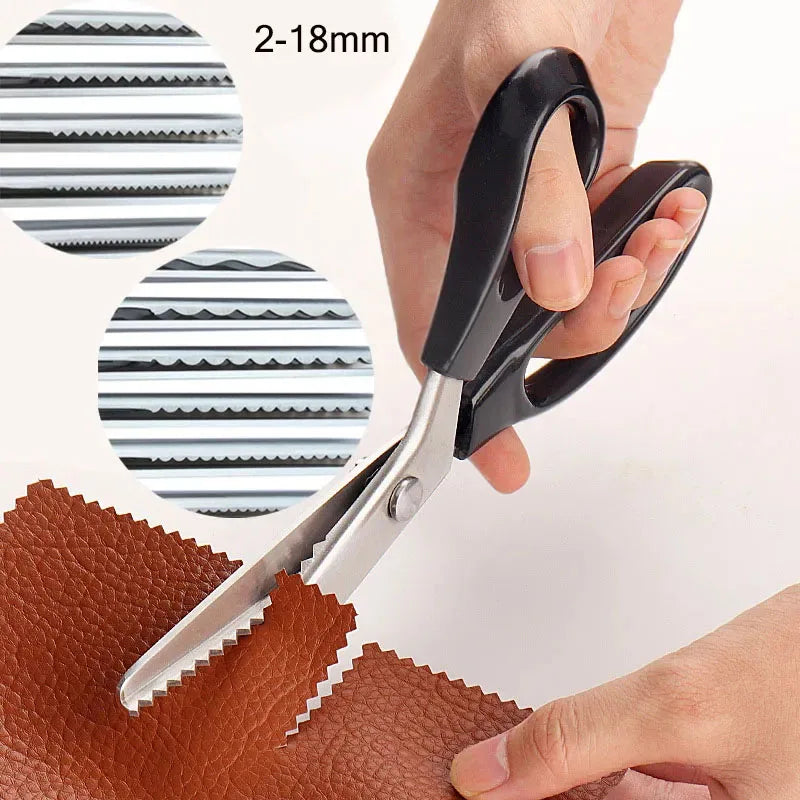 A pair of black and silver pinking shears are shown cutting into brown leather fabric.