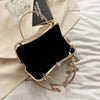 A gold-toned envelope clutch with a chain strap resting on a light fabric background.