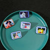A collection of enamel pins featuring characters from SpongeBob SquarePants and Captain Patrick Star displayed on a green pla