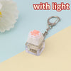 A clear plastic LED mechanical keychain fidget toy with a pink paw print keycap and silver keyring.
