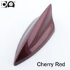 A glossy, aerodynamic car antenna shaped like a shark fin in cherry red piano paint.