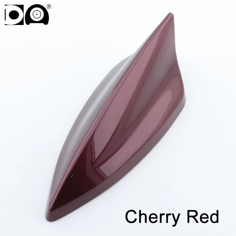 A glossy, aerodynamic car antenna shaped like a shark fin in cherry red piano paint.