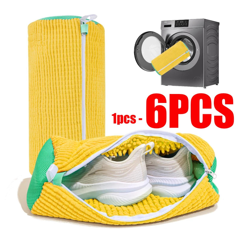 A yellow reusable shoe laundry bag with a brush and a pair of white sneakers is shown next to a washing machine.