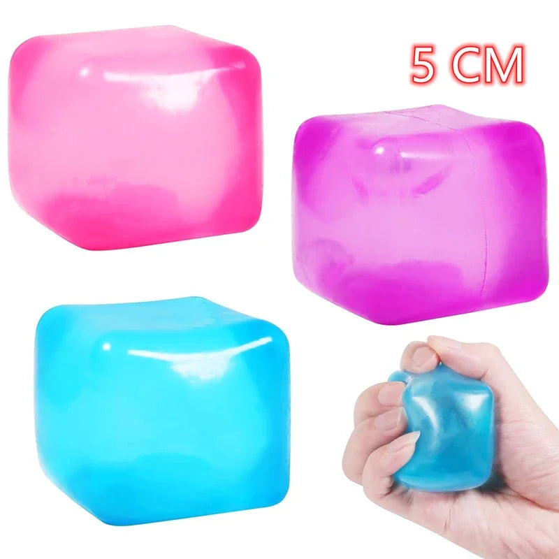 Drei bunte, weiche Spielzeuge in Pink, Lila und Blau mit einer Hand zur Skalierung.