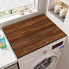 A close-up view of a wood grain waterproof washer and dryer mat placed inside a white washing machine.