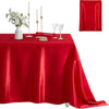 A red satin tablecloth set for dining or parties, featuring a centerpiece with white flowers and tall candles.