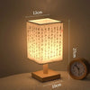 A Chinese style dimmable table lamp with a light-colored linen shade sits on a wooden base.