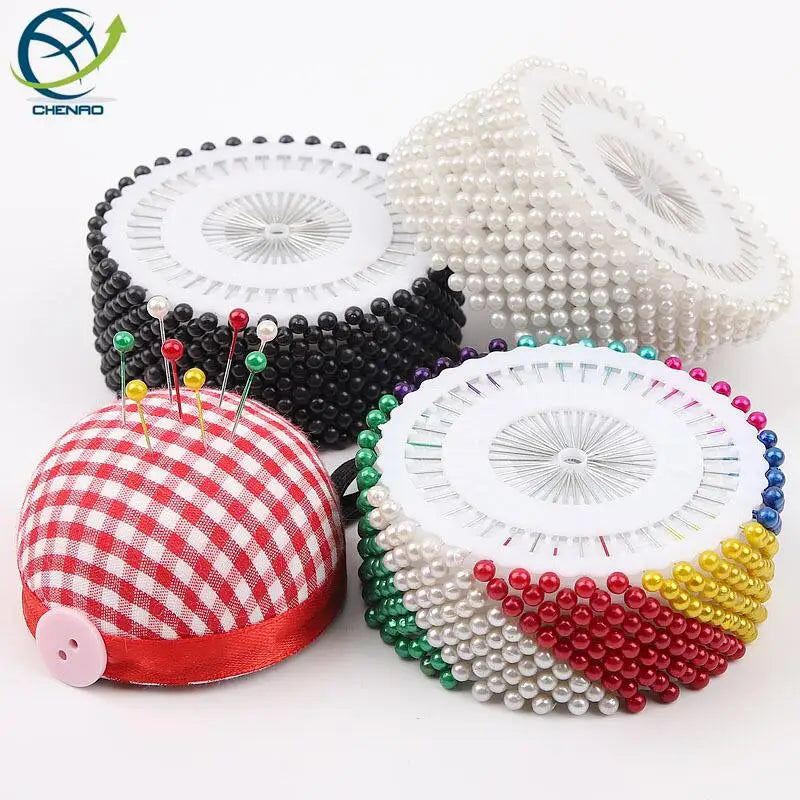 A collection of colorful round pearl straight pins for sewing and crafts, including red and white checkered pins and various 