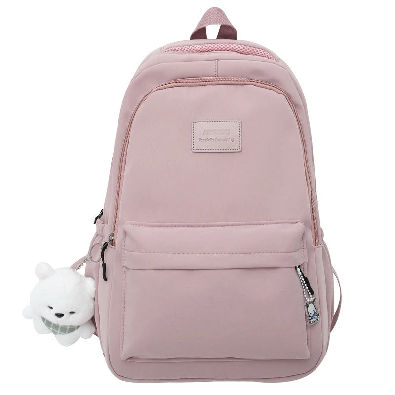A pink waterproof nylon laptop backpack with a white bear charm