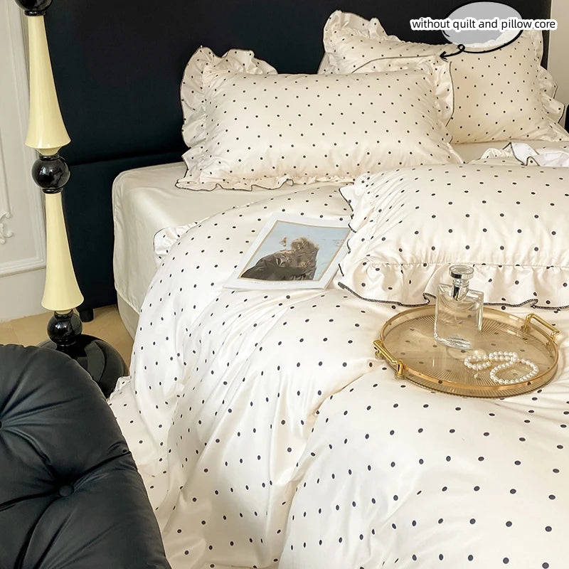 A set of three white bedding pieces featuring a black dot print, including a duvet cover and pillows.