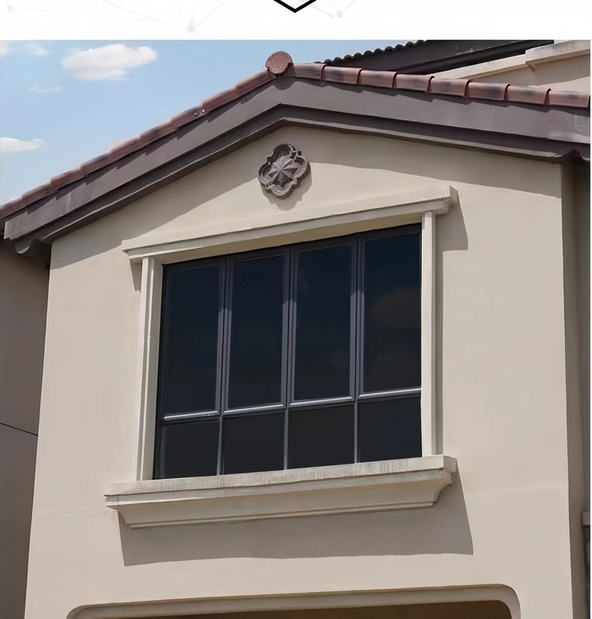 A close-up of a modern building exterior featuring a rectangular window with dark tinting and decorative trim.