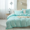 Light aqua duvet cover set with pom-pom trim on a bed in a bright room.