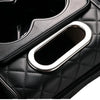 Close-up of a black quilted car center console armrest cushion featuring a silver cup holder and storage pockets.