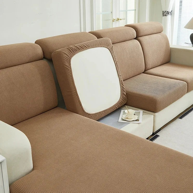 A beige Jacquard stretch sofa slipcover with a white back and light wood accents.