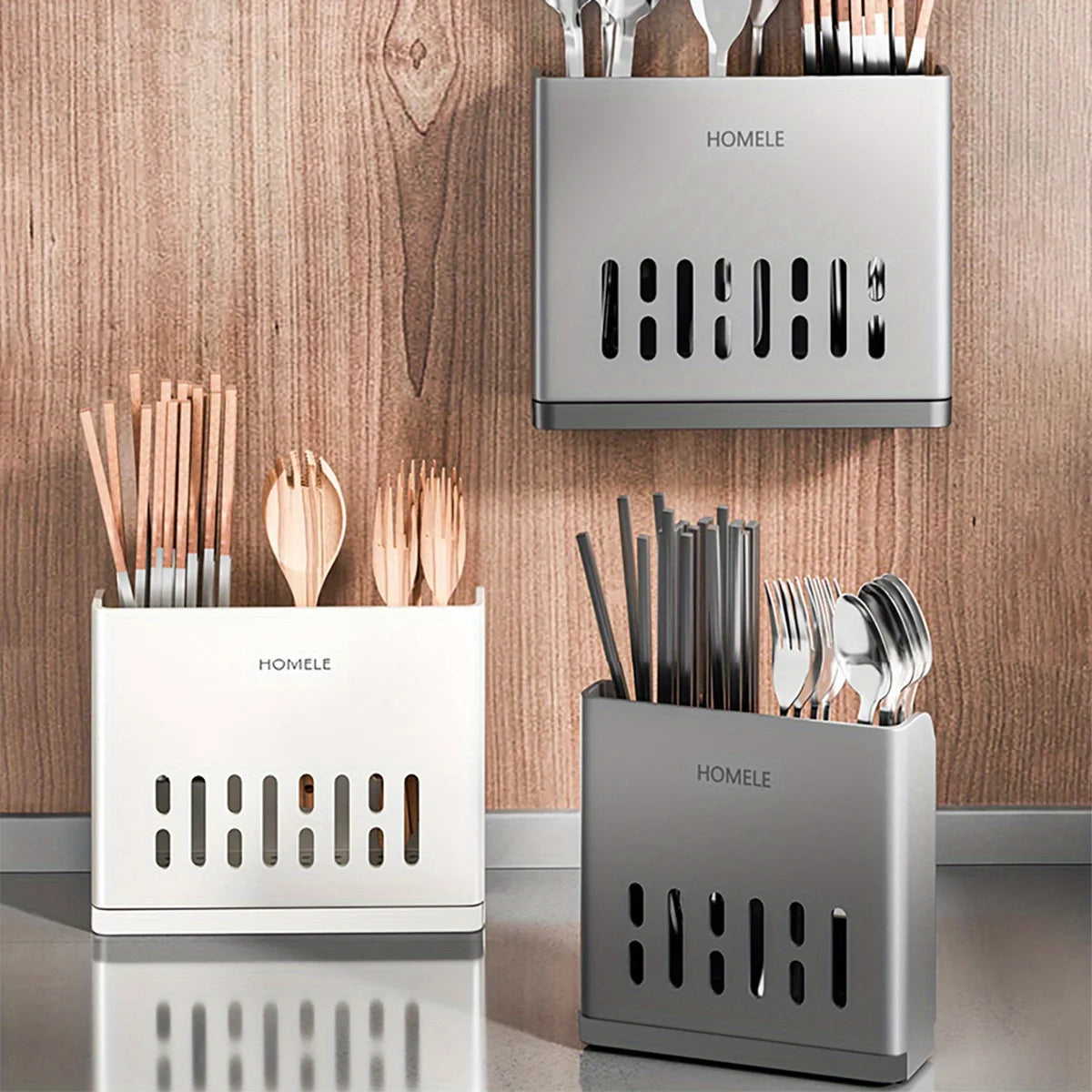 Three stainless steel cutlery organizers in silver and white tones displayed against a wooden background.
