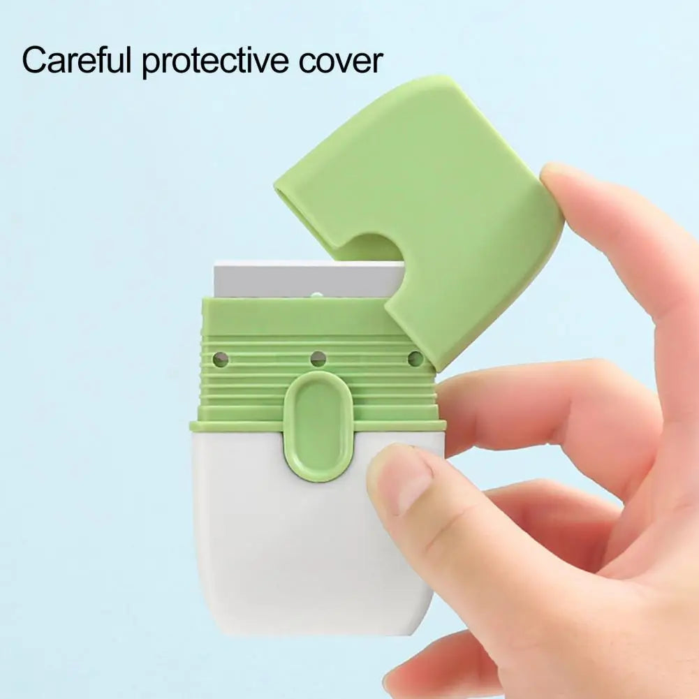 A hand is holding a white cleaning scraper with a green protective cover on it.