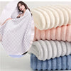 A stack of fluffy microfiber towels in various shades of white, pink, and blue are displayed next to a woman using a white to