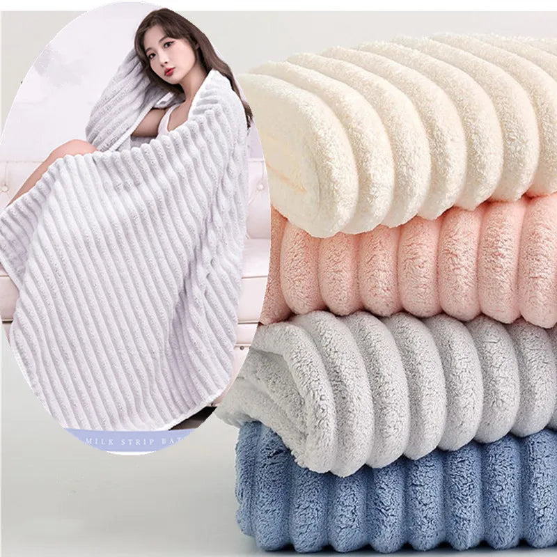 A stack of fluffy microfiber towels in various shades of white, pink, and blue are displayed next to a woman using a white to