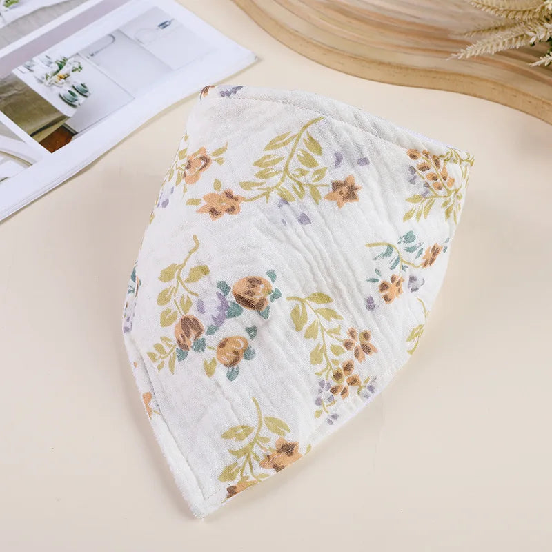 A white cotton baby bib with a floral pattern is shown on a light background.