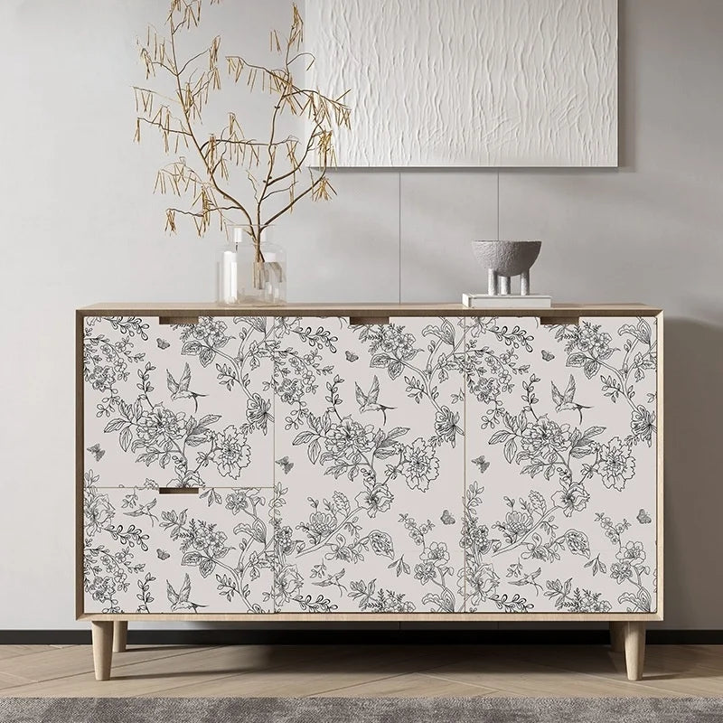 A wooden cabinet featuring a botanical line art wallpaper with gray and white floral designs.