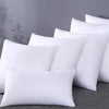 A stack of white square cushions with a smooth texture resting on a gray surface.