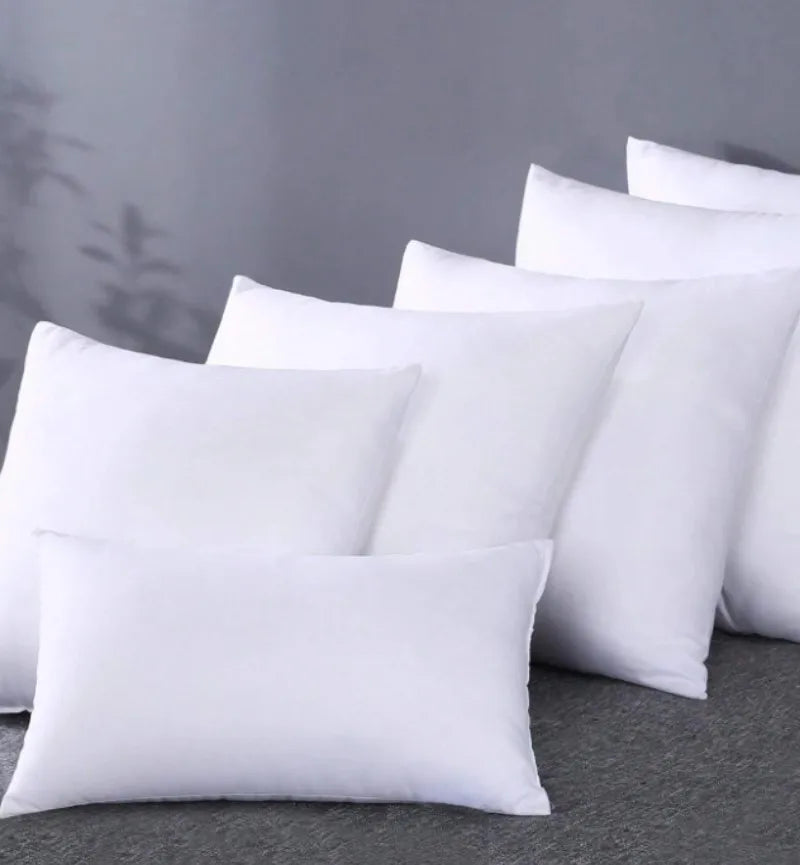 A stack of white square cushions with a smooth texture resting on a gray surface.