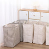 Three striped laundry baskets in beige and white fabric lined up next to a wooden dresser.