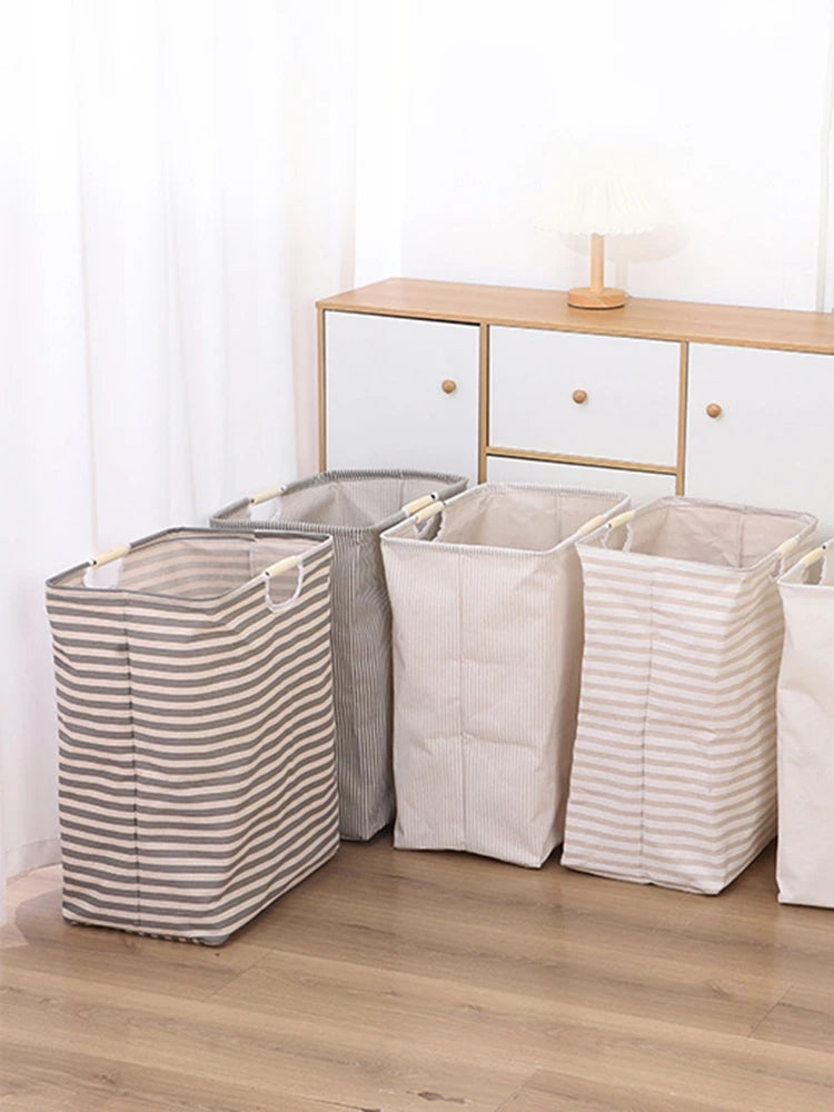 Three striped laundry baskets in beige and white fabric lined up next to a wooden dresser.