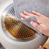 A hand is using a gray steel wire scrubber dishcloth to clean a round, silver dish.